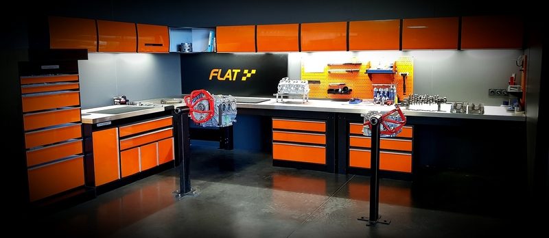 Atelier moteur FLAT aux établis orange et noirs, moteurs flat-six sur supports de montage