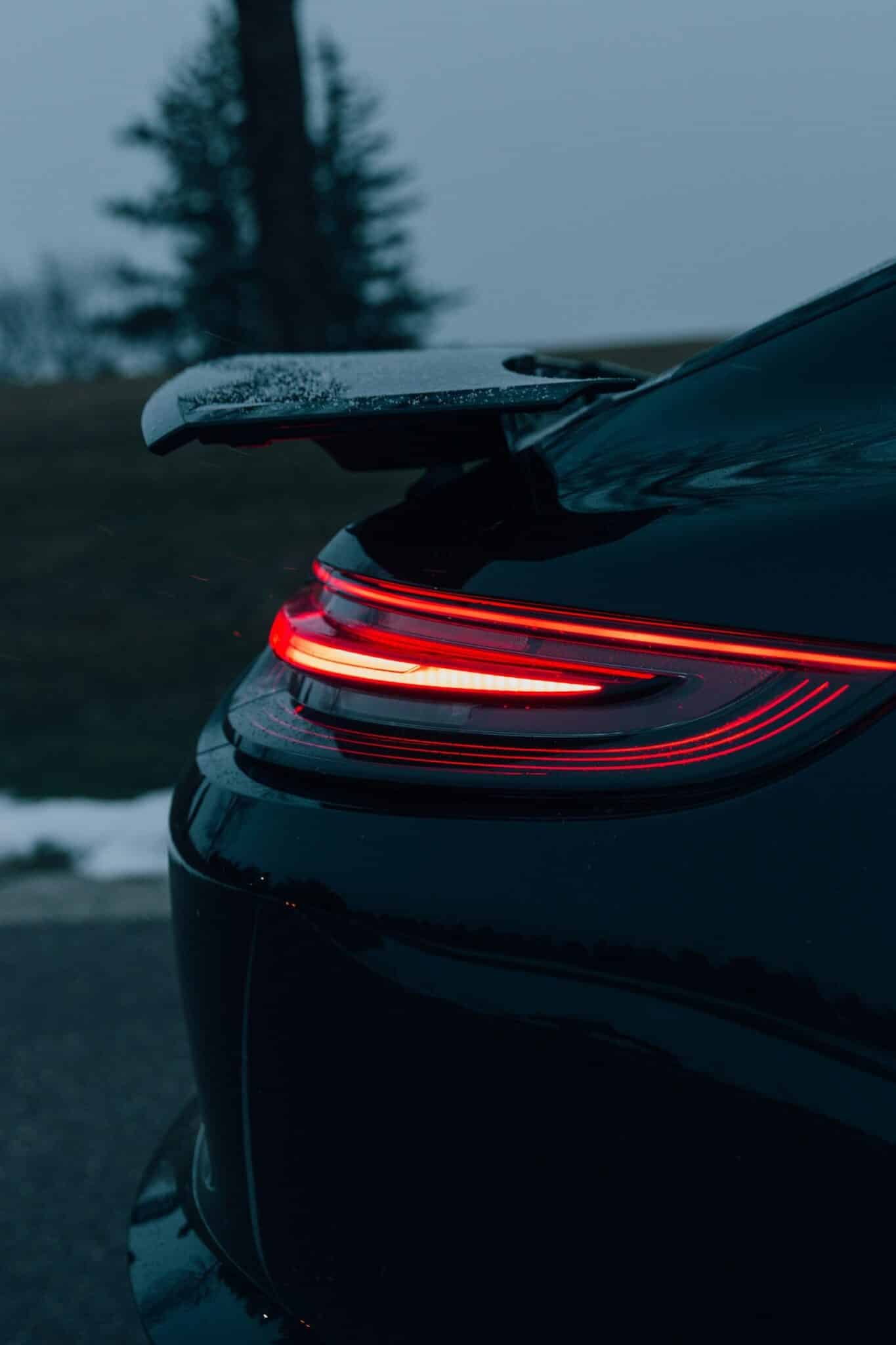Détail du feu arrière rouge d'une Porsche 911 noire au crépuscule
