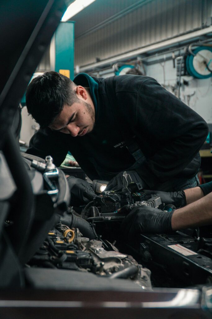 Mécanicien penché sur le compartiment moteur d'une voiture dans un atelier