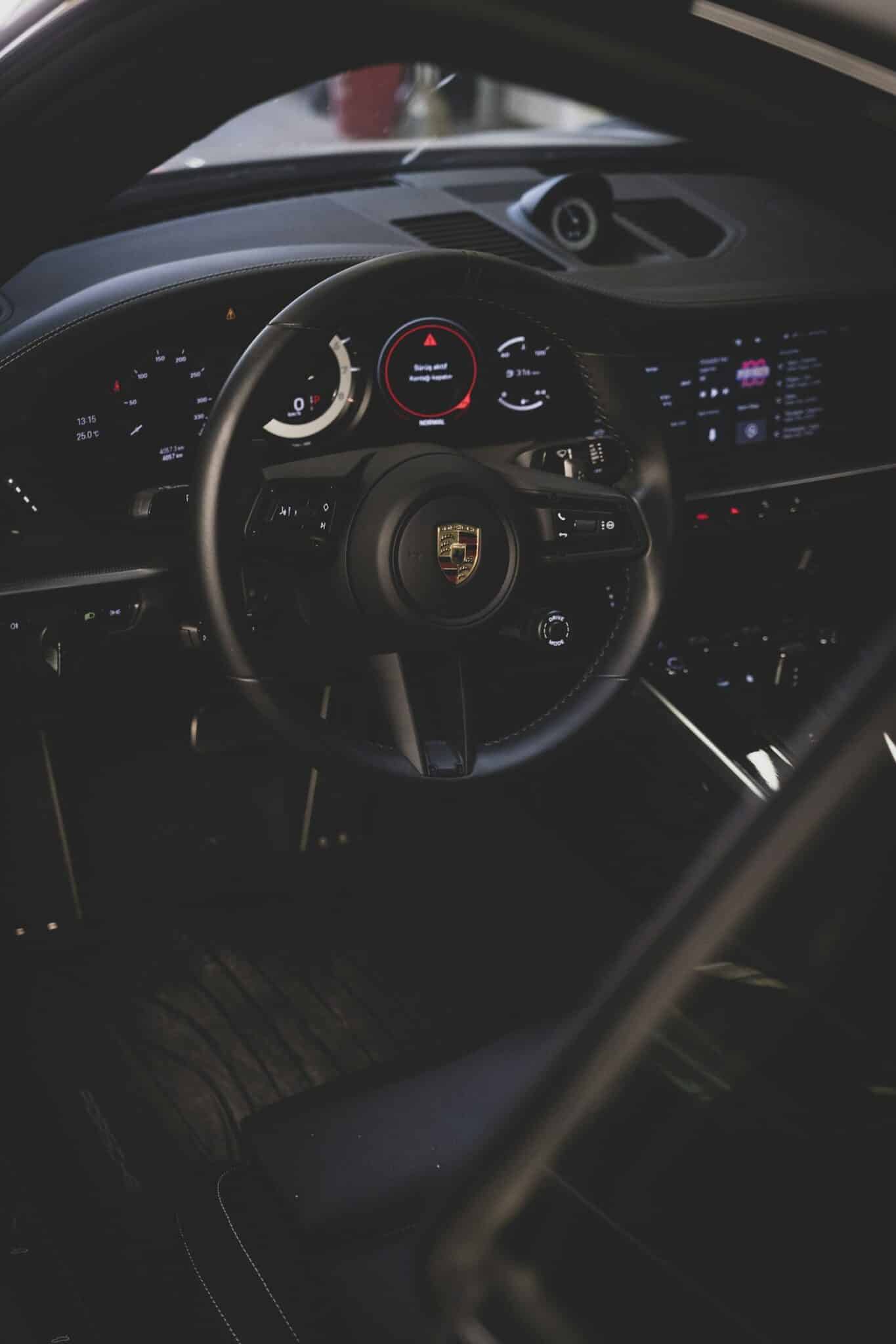 Poste de conduite d'une Porsche 911 récente, volant et compteurs dans la pénombre