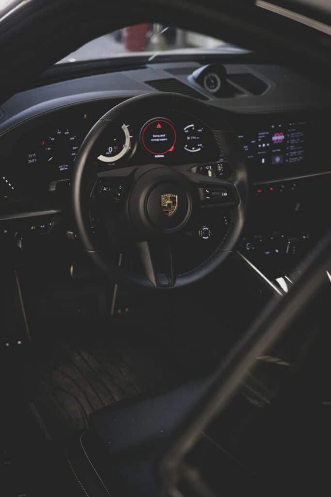 Poste de conduite d'une Porsche 911 récente, volant et compteurs dans la pénombre